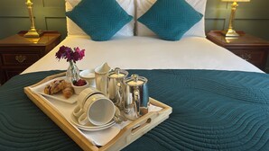 A neatly made bed with teal bedding, two matching pillows, and a tray with breakfast items including croissants, coffee cups, and a vase of flowers. - Abbey Hotel Roscommon (Roscommon)