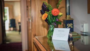 A reception desk with a vase of flowers, a card, and a decorative lamp.