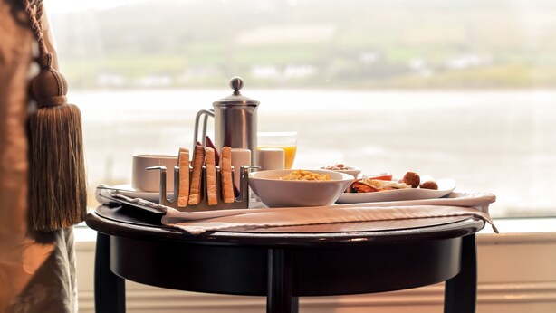 Uma mesa de café da manhã com uma cafeteira, utensílios e alimentos.