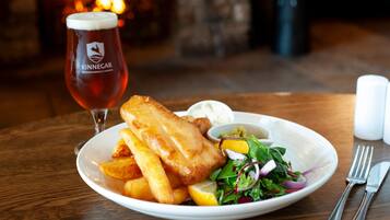 Ein Teller Fish and Chips mit Salat und einem Glas Bier.