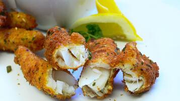 A plate of breaded and fried fish pieces with a lemon wedge and parsley garnish.
