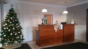 A reception desk with a Christmas tree and a mirror above it.