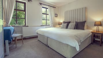 Un dormitorio con una cama grande, dos mesitas de noche con lámparas, una silla y una ventana con cortinas.