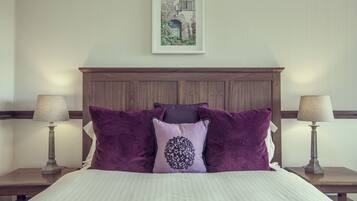 A neatly made bed with a headboard, two bedside tables with lamps, and a framed picture on the wall.