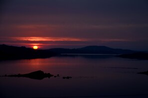 Un atardecer sobre un lago tranquilo con montañas a lo lejos.