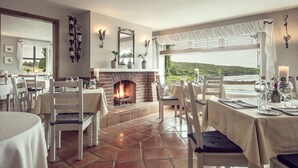 A dining area with a fireplace, white furniture, and a view of the landscape. - The Ardagh Hotel & Restaurant (Clifden)