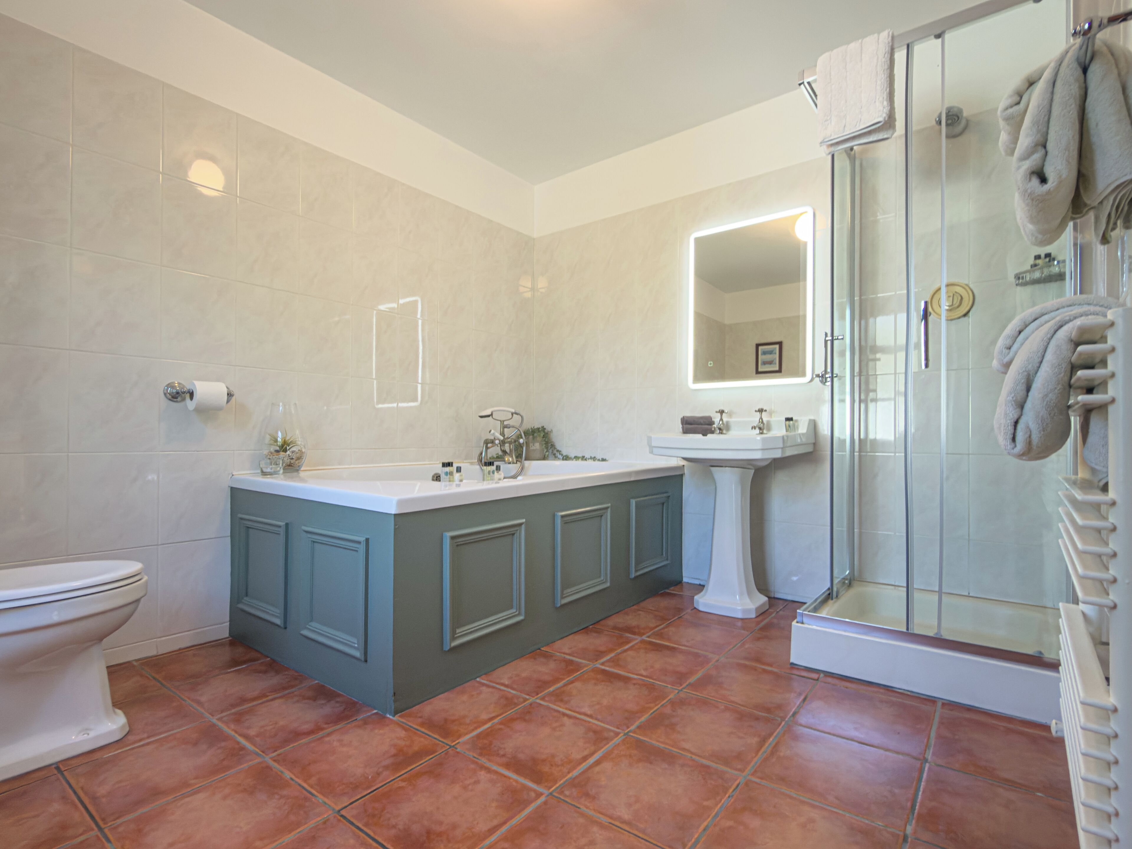 A bathroom with a toilet, a sink, a mirror, and a shower.