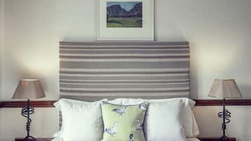 A neatly made bed with striped bedding, two bedside lamps, and a pillow with a bird pattern.