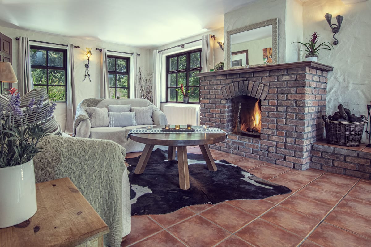 A cozy living room with a fireplace, a sofa, a coffee table, and a potted plant.