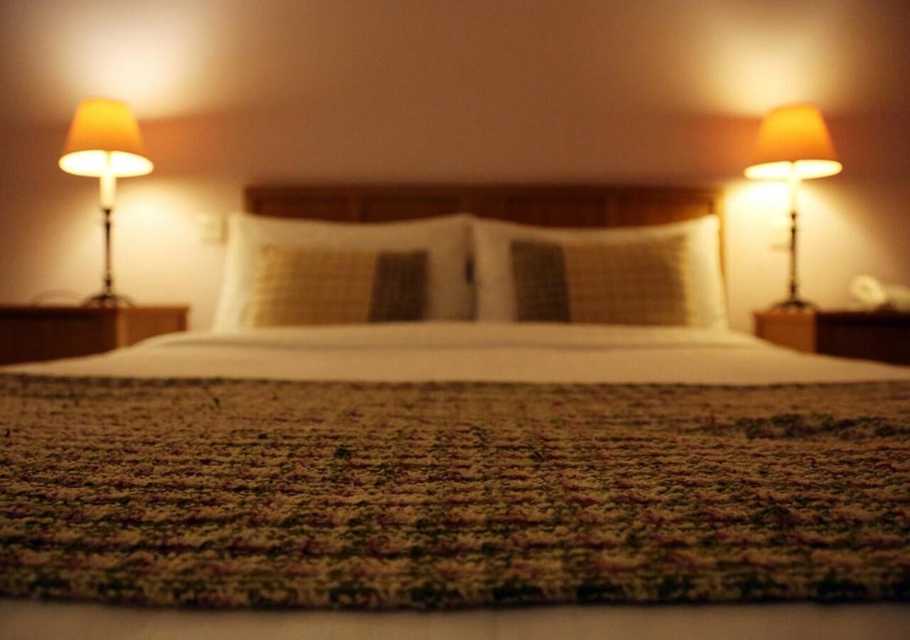Un lit avec une couvre-lit à motifs, deux lampes de chevet et une tête de lit.