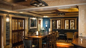 A dining area with a wooden table and chairs, a stone wall, and a blue accent wall. - Castle Hotel Macroom (Macroom)