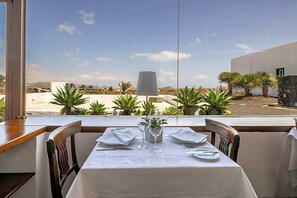 A dining table set with white tablecloth, plates, and cutlery, with a lamp and potted plants on the table. - Norfolk Plaza (London)