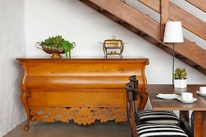 A wooden bench with a decorative backrest, a brass object, and a potted plant on a table. - Norfolk Plaza (London)