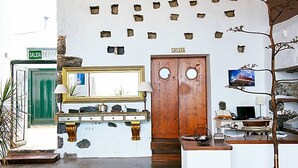 A reception area with a wooden door labeled 'COCINA', a mirror above a console table, and a sign reading 'SALIDA'.