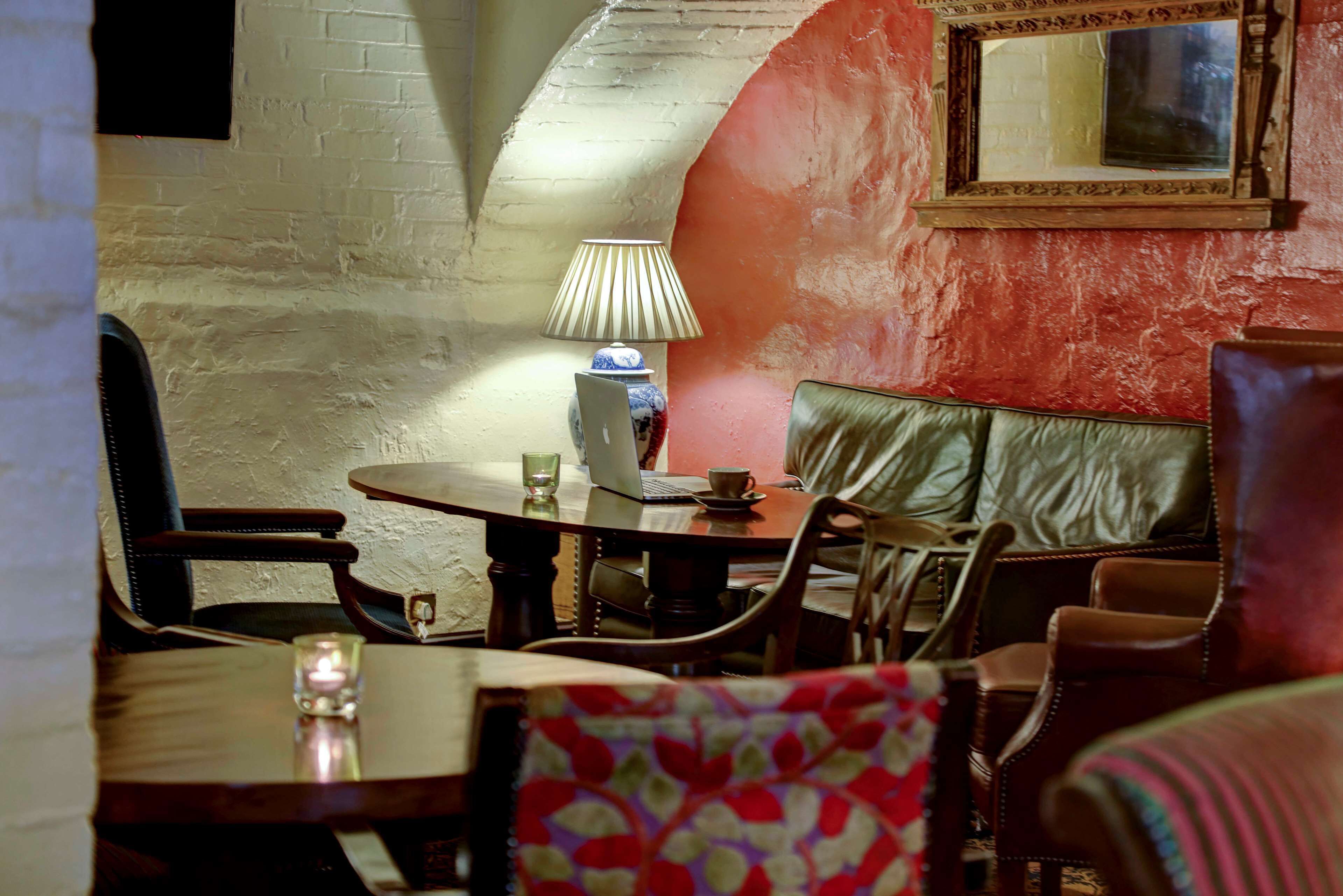 A cozy dining area with a round table, chairs, a laptop, and a lamp.
