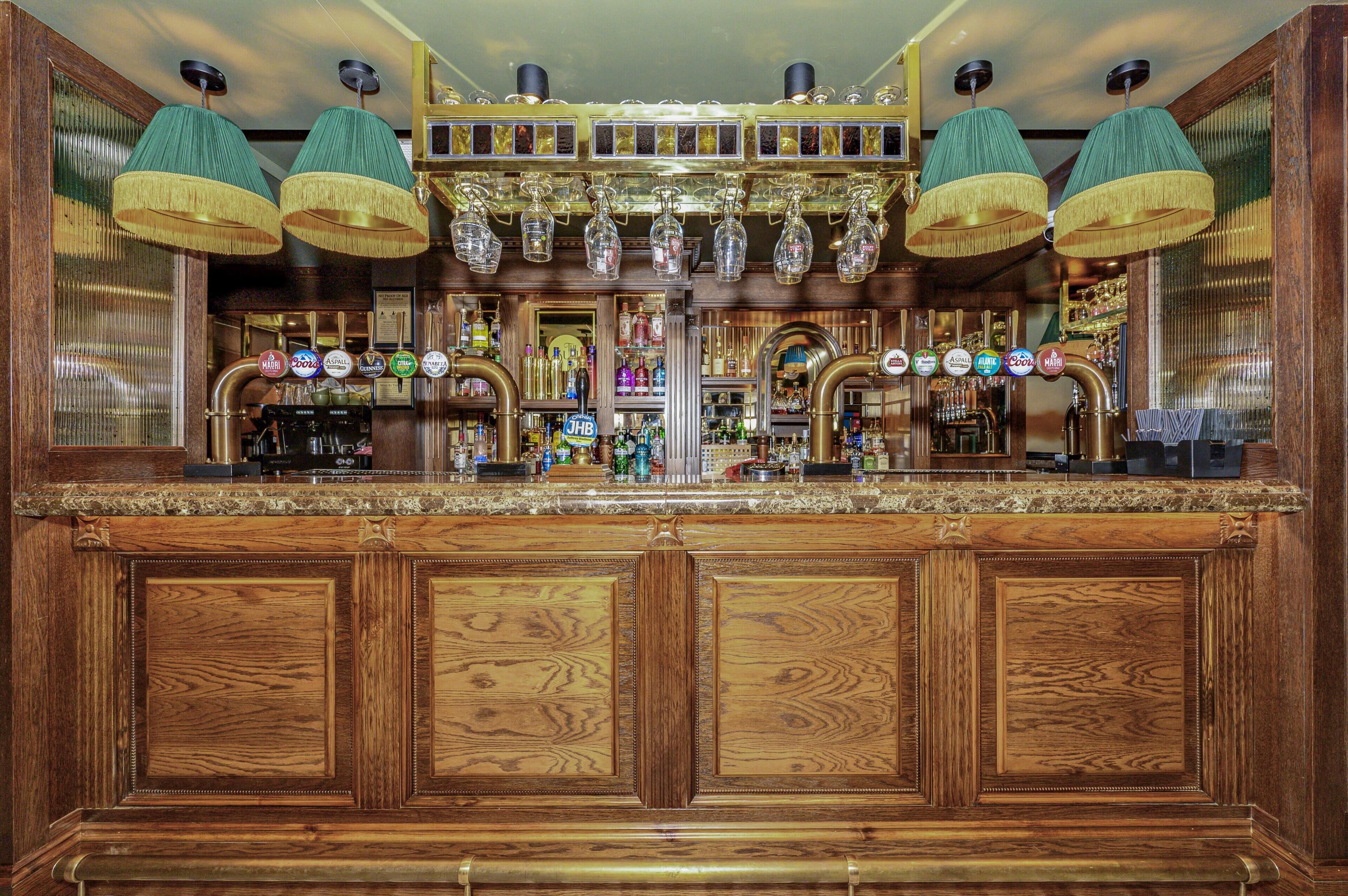 A bar with wooden paneling, multiple taps, and hanging lamps.