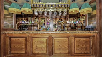 A bar with wooden paneling, multiple taps, and hanging lamps.