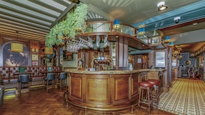 Un espace bar avec un comptoir en bois, des tabourets et une plante suspendue.