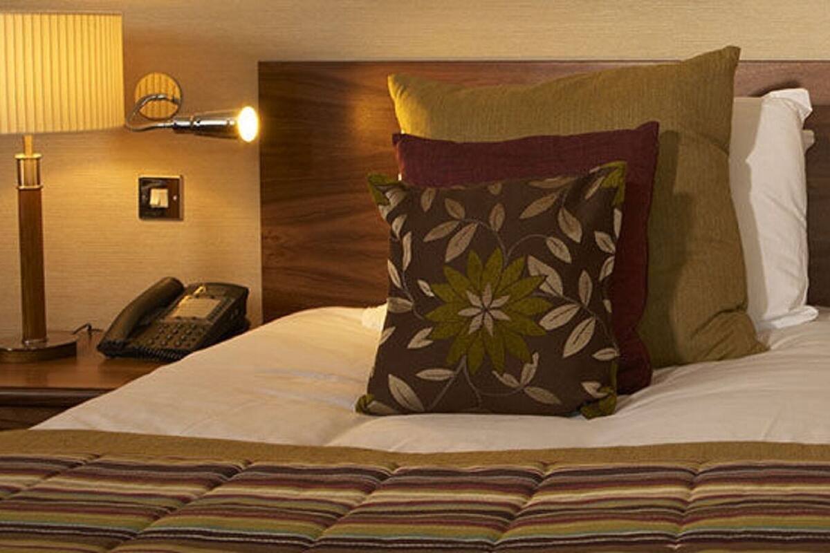 A neatly made bed with floral-patterned pillows, a striped bedspread, and two bedside lamps on wooden nightstands.