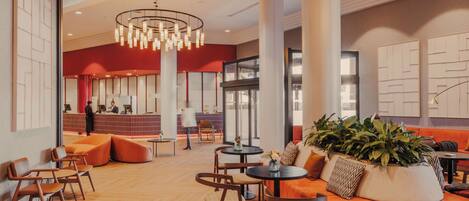 A spacious lobby with a reception desk, seating areas, and a large plant centerpiece.