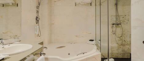 A modern bathroom with a marble floor, a large bathtub, a glass-enclosed shower, and a vanity with a mirror.