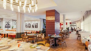 Un restaurant moderne doté d’un plancher en bois, de tables rondes et d’un éclairage contemporain.