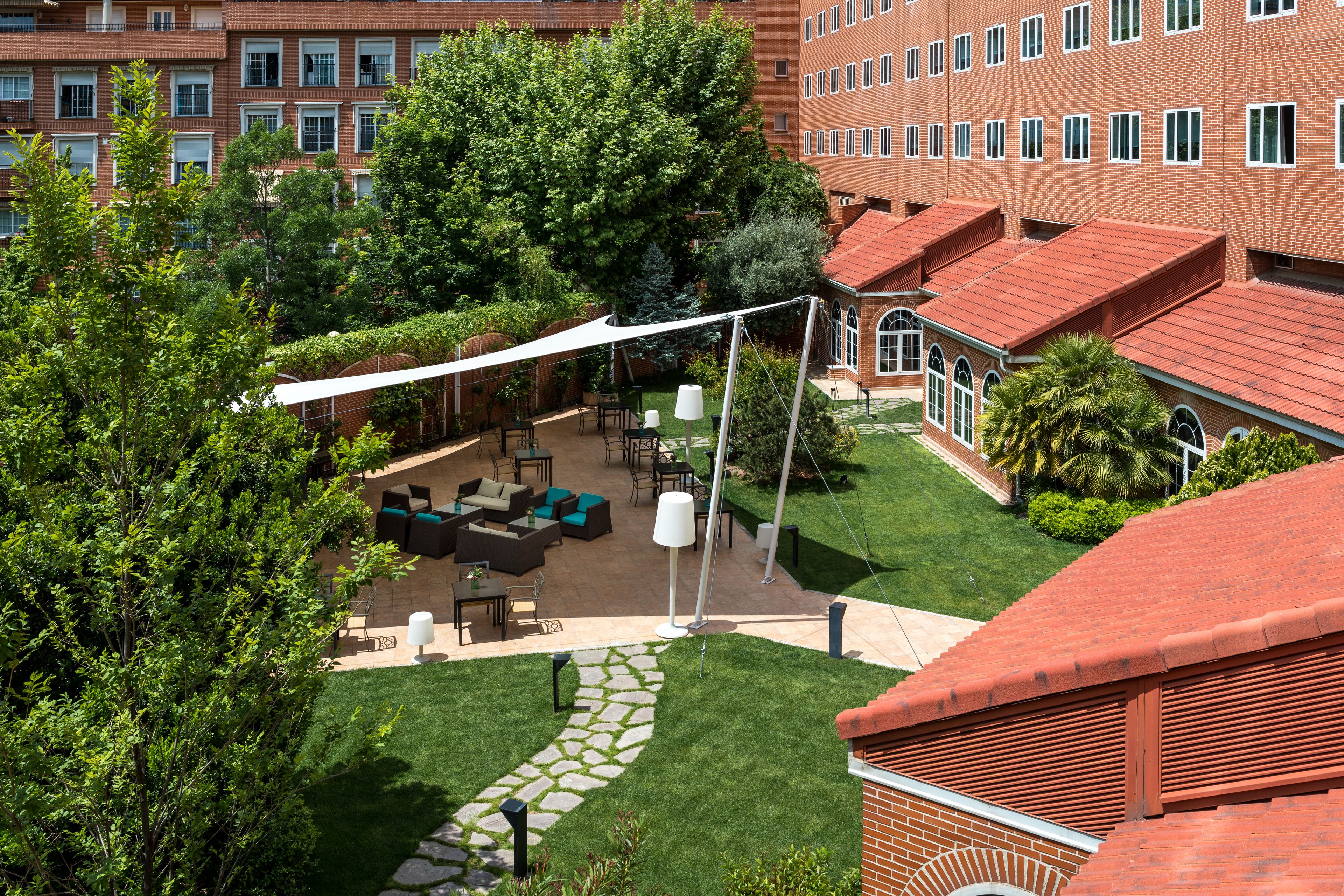 A courtyard with outdoor seating, a white canopy, and a brick building in the background.