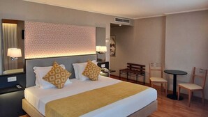 Una habitación de hotel con una cama grande, mesitas de noche, un escritorio y una silla.