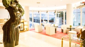 Un moderno vestíbulo de hotel con una escultura, zonas de estar y ventanas amplias.