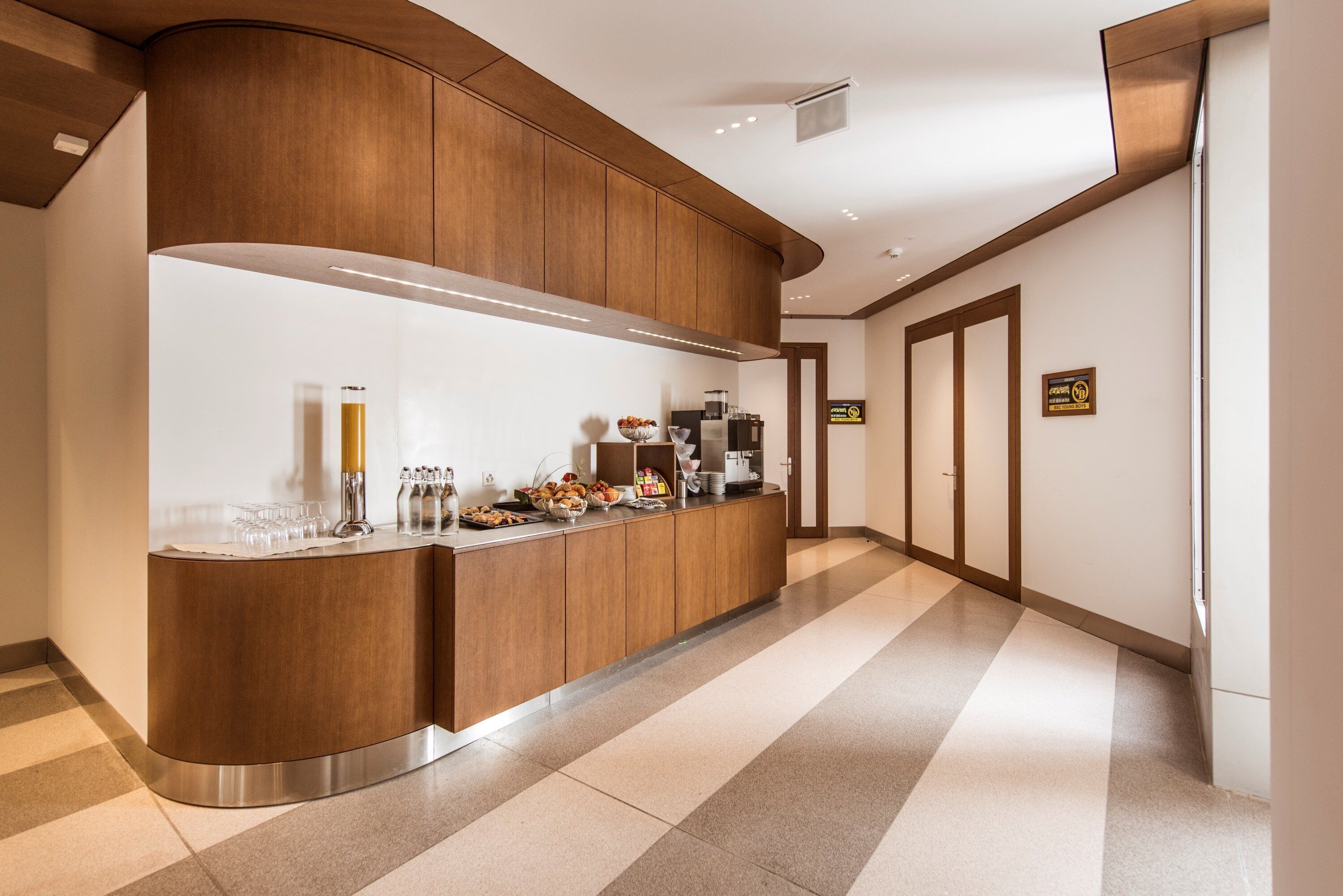 A modern kitchen with a curved wooden counter, stainless steel appliances, and a tiled floor.