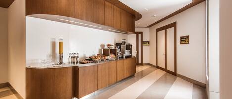 A modern kitchen with a curved wooden counter, stainless steel appliances, and a tiled floor.