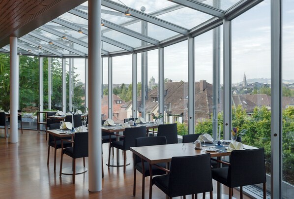 A spacious indoor dining area with large windows offering a view of the cityscape.