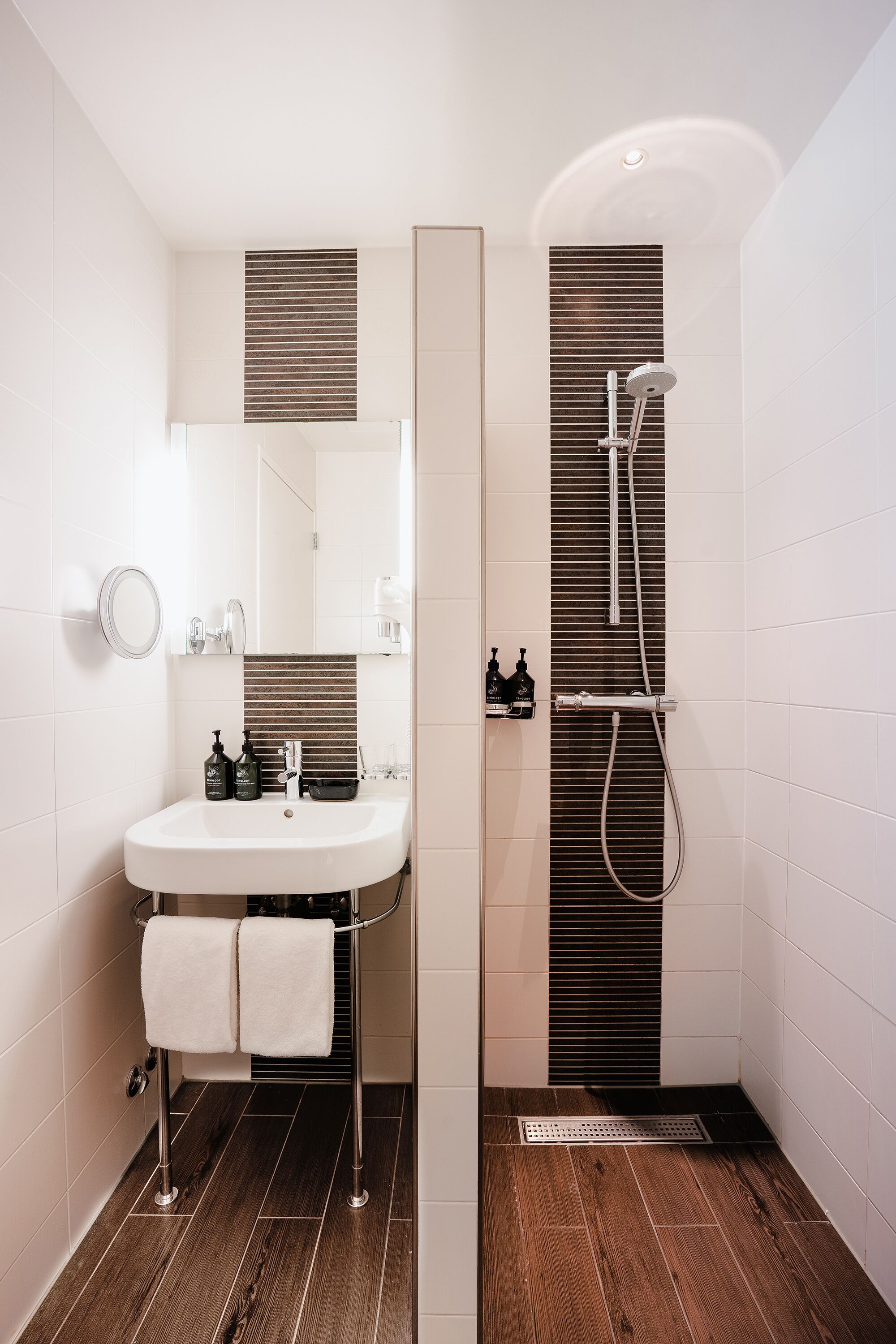 A modern bathroom with a white sink, mirror, and shower.