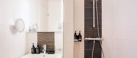 A modern bathroom with a white sink, mirror, and shower.