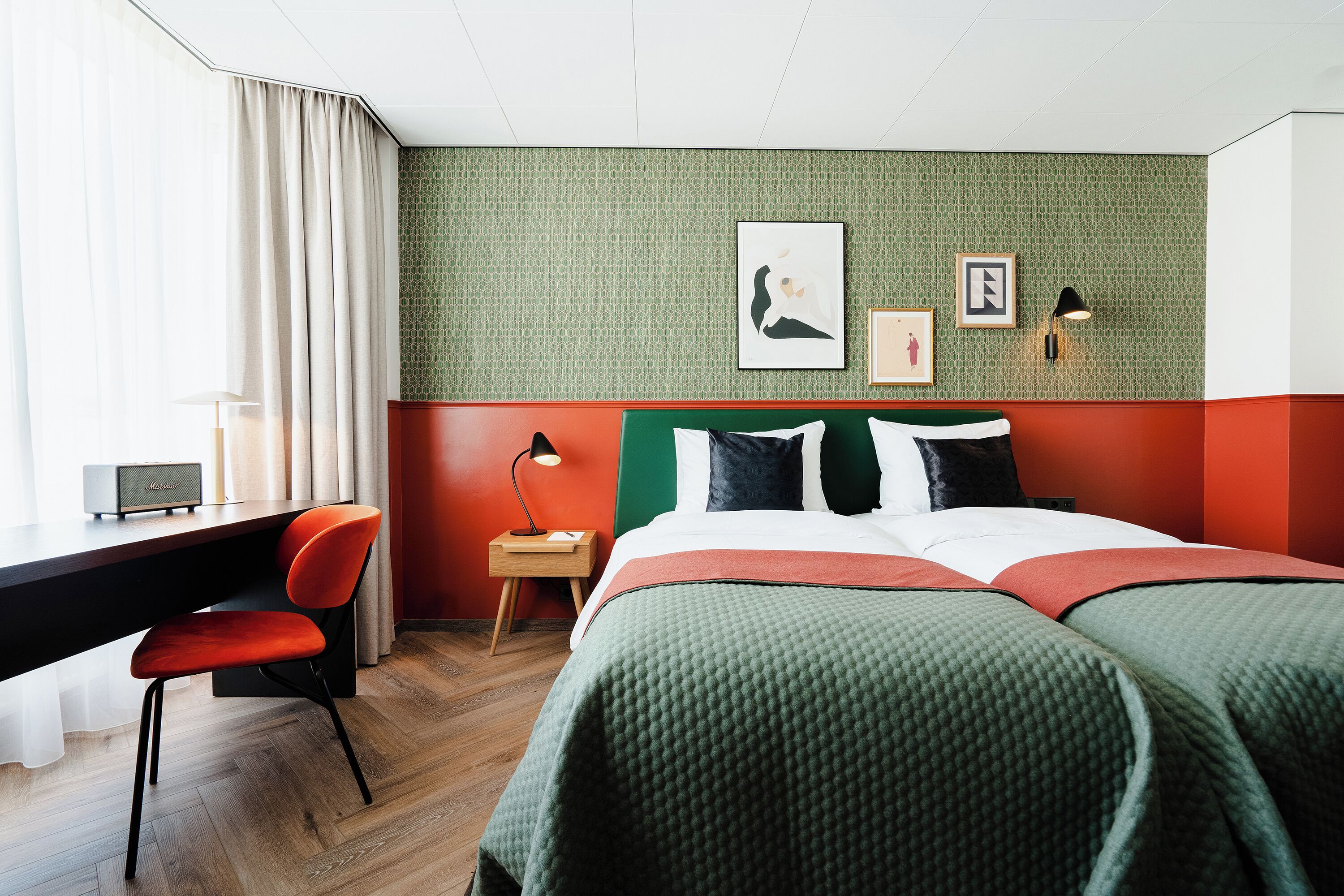 Ein Hotelzimmer mit Bett, Schreibtisch, Stuhl, Nachttisch und Lampe.