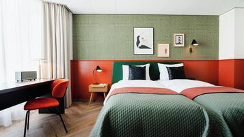 Une chambre d’hôtel comprenant un lit, un bureau, une chaise, une table de chevet et une lampe.