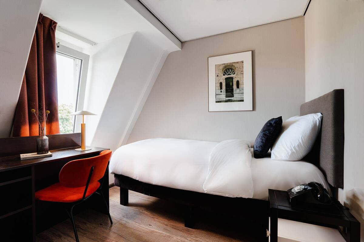 Ein modernes Hotelzimmer mit Bett, Schreibtisch und Stuhl.