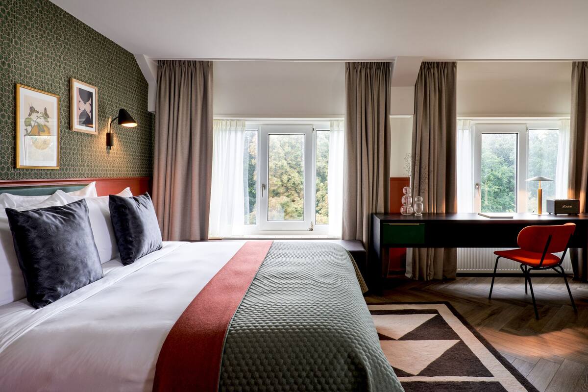 Ein Hotelzimmer mit Bett, Schreibtisch, Stuhl und großen Fenstern.