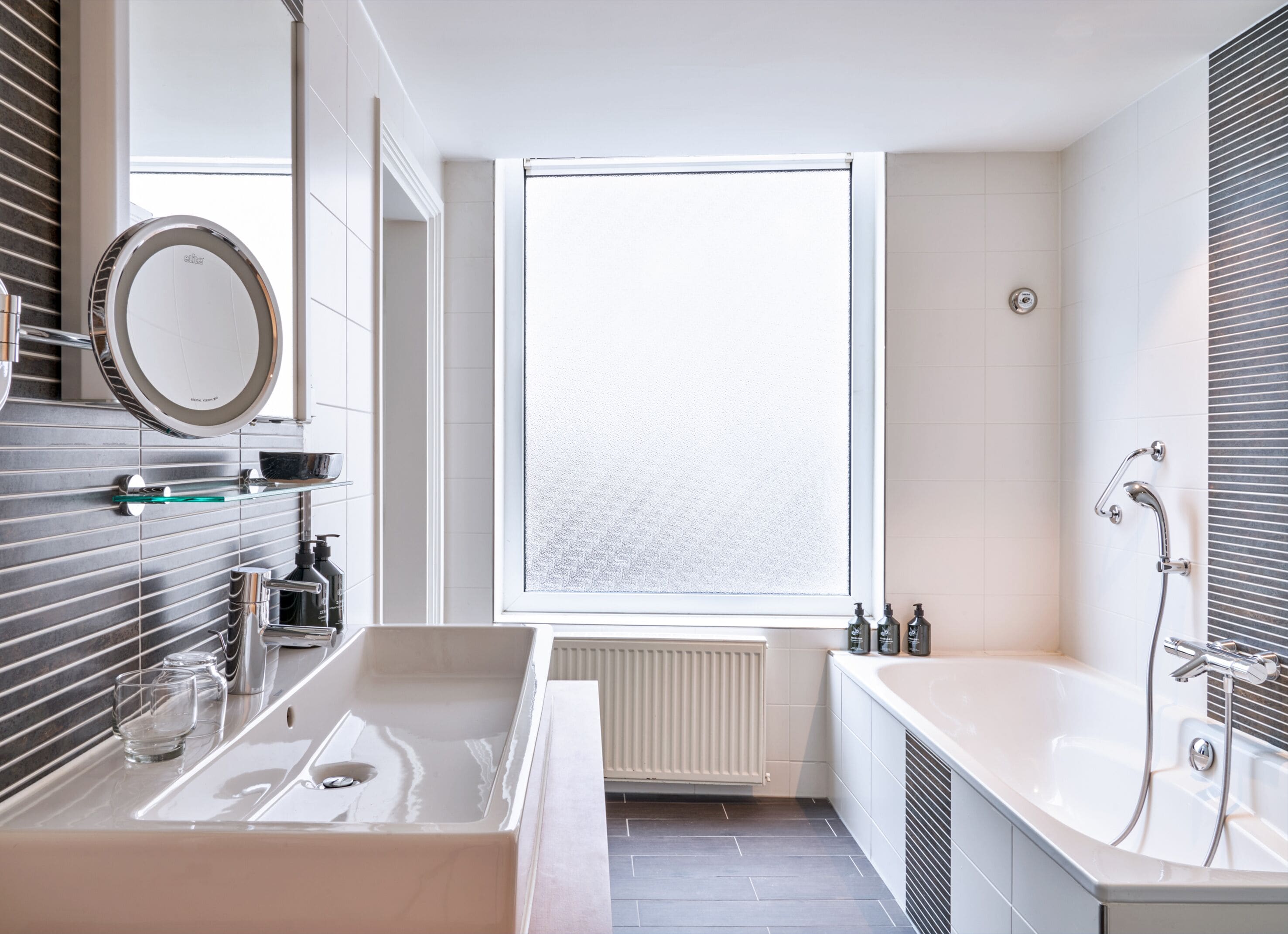 A modern bathroom with a large bathtub, a separate shower area, and a window providing natural light.