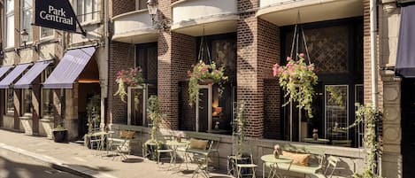 An outdoor seating area with tables and chairs, a hanging flower basket, and a sign reading "Park Centraal".