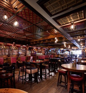 A bar with wooden ceiling and hanging light fixtures, bar stools, and a variety of liquor bottles. - Arlington Hotel O'Connell Bridge (Dublin)