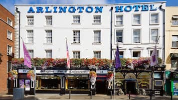 Esterno dell'Arlington Hotel con un bar e un ristorante al piano terra, bandiere e fioriere.