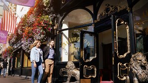 A building entrance with ornate black doors, a lion statue, and a floral display. - Arlington Hotel O'Connell Bridge (Dublin)