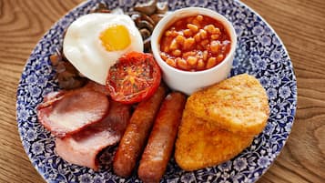 Un plato de comida para el desayuno con huevos, salchichas, tocino, frijoles y tostadas.