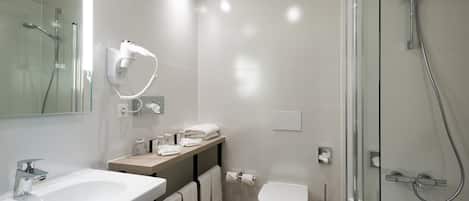 Ein modernes Badezimmer mit einer Duschkabine, einem weißen Waschbecken und einer Toilette.