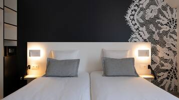 A double bed with two pillows, bedside tables with lamps, a black and white patterned wall, and a dark headboard.