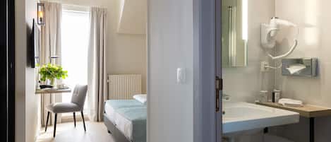 A modern hotel room with a desk, chair, and a bed.