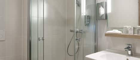 A modern bathroom with a glass-enclosed shower, a white sink, and a mirror above the sink.