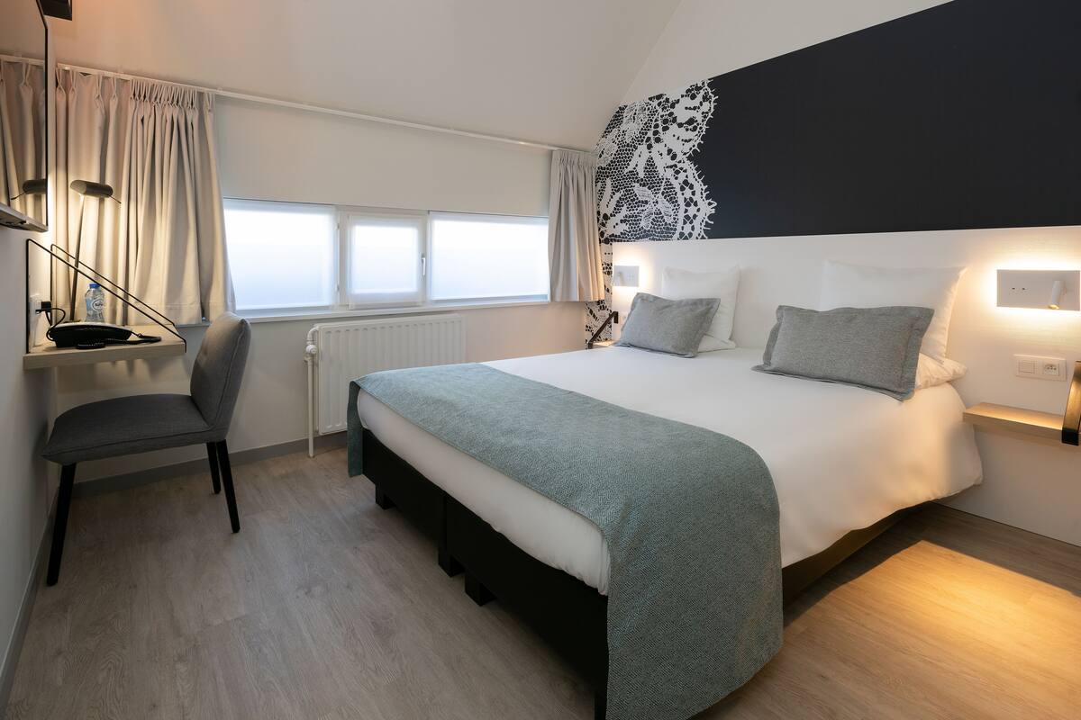 Une chambre d’hôtel moderne, dotée d’un grand lit, d’un bureau et d’une chaise.