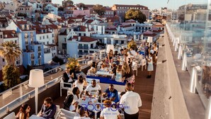 Un bar en la azotea con mesas al aire libre con vistas a una zona urbana concurrida.